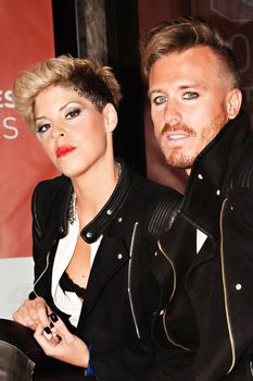 Fashionable young couple sitting at the bus stop with defiant look. Urban fashion photography. Vertical image.