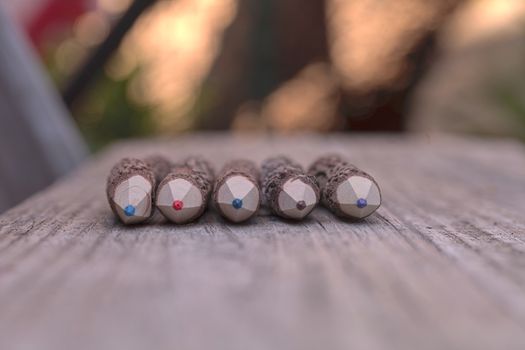 Macro view of bark covered colored pencil tips on a wood bench background