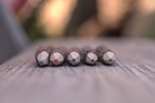 Macro view of bark covered colored pencil tips on a wood bench background