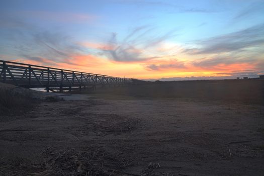 Wooden Boardwalk at sunset, to journey through Bolsa Chica Wetlands preserve in Huntington Beach, California, United States