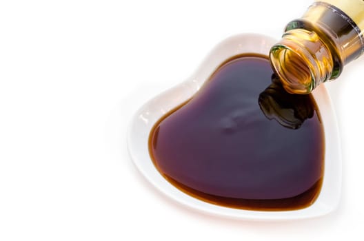 Oyster sauce in white cup heart shape on white background.