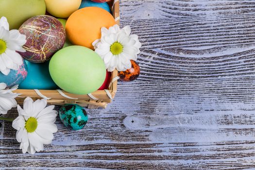 Easter painted eggs in basket with flowers, easter background