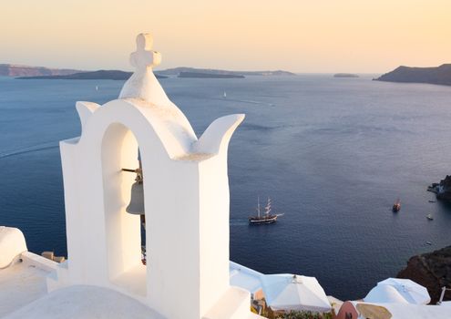 World famous traditional whitewashed chuche of Oia village on Santorini island, Greece. Sunset light.