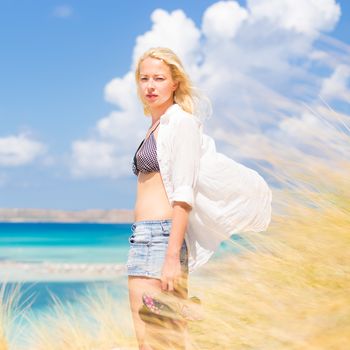 Relaxed woman enjoying freedom and life an a beautiful sandy beach.  Young lady feeling free, relaxed and happy. Concept of freedom, happiness, enjoyment and well being.  Enjoying Sun on Vacations.