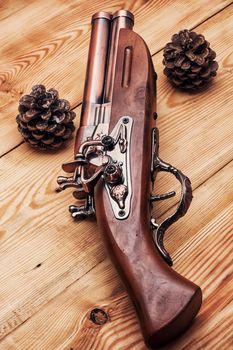 Old hunting musket on a light wooden background with forest cones