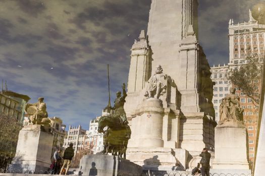 Reflection in water of stone statue of Miguel de Cervantes and bronze sculptures of Don Quixote and Sancho Panza on the Square of Spain (Plaza de Espana) in Madrid.