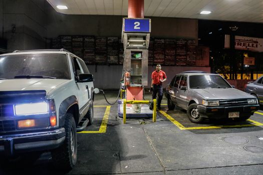 VENEZUELA, Caracas: An employee of a gas station fills cars in Caracas, on February 17, 2016. Venezuela's President Nicolas Maduro said Wednesday he would raise the price of gasoline for the first time in 20 years, as he faces growing pressure to ease an economic crisis. Maduro said in a televised address he would raise the pump price of premium gasoline from its current super-low level of $0.01 to the equivalent of $0.95 at the fixed official exchange rate, in a country where citizens are struggling with soaring inflation.