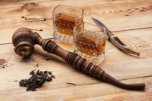 Smoking pipe in a retro style,dark chocolate and glasses of whiskey on wooden background