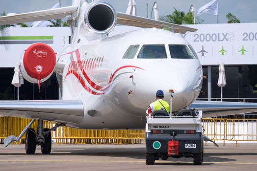 Singapore - February 14, 2016: Tri engine Dassault Falcon 7X being pushed into position before the opening of Singapore Airshow at Changi Exhibition Centre in Singapore.