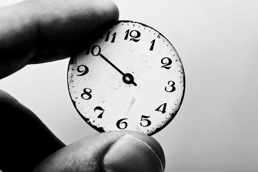 Black and white picture of two fingers holding a clock dial
