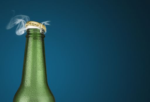 Horizontal photo of a green cold beer bottle with water drops and golden cap open on blue background