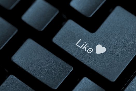 Horizontal close up of black keys on a keyboard with the word like and a heart icon on one of them