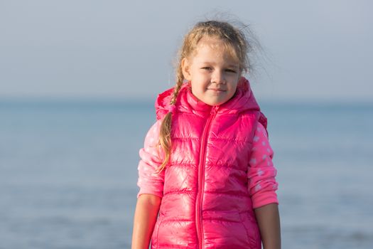 Portrait of a four-year girl in a jacket cooler early morning on the beach