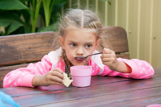 Girl sitting at a wooden table on the porch, and breakfast