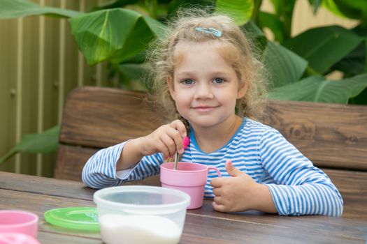 Four-year girl sitting at a wooden table on the porch, and breakfast