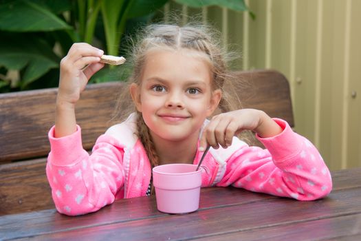 Girl sitting at a wooden table on the porch, and breakfast