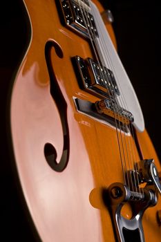 Vertical close up of an orange electrical guitar on black background
