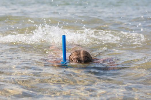 Six-year girl swims with a mask and snorkel under water at the seaside
