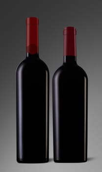 Two red wine bottles with caps and no label on grey background