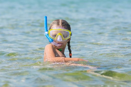 Six-year girl swims with a mask and snorkel under water at the seaside
