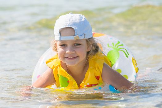 Four-year girl swims in the summer with a lifeline and vest in the sea