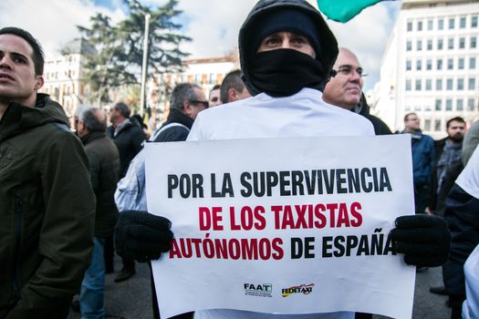 SPAIN, Madrid: A protester holds a sign which reads 'For the survival of Spain's autonomous taxis' as thousands of taxi drivers demonstrate against deregulation and ride-hailing companies such as Uber, in Madrid, on February 18, 2016.
