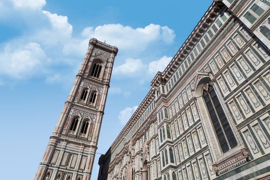 Bottom view of belfry tower of Florence Duomo, Santa Maria Del Fiore, on cloudy blue sky background.