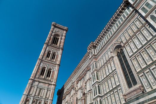 Bottom view of belfry tower of Florence Duomo, Santa Maria Del Fiore, on bright blue sky background.