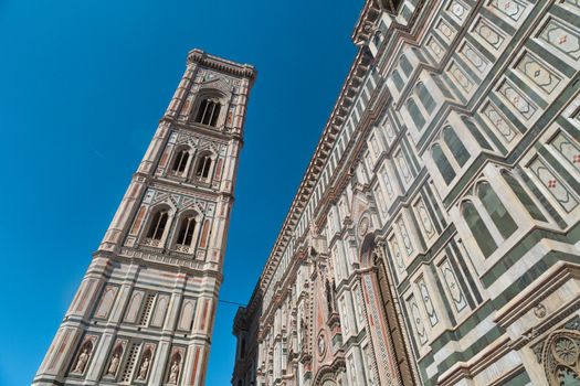 Bottom view of belfry tower of Florence Duomo, Santa Maria Del Fiore, on bright blue sky background.