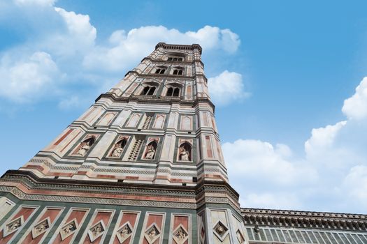 Bottom view of belfry tower of Florence Duomo, Santa Maria Del Fiore, on cloudy blue sky background.