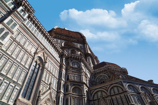 Bottom view of famous historical Florence Duomo, Santa Maria Del Fiore, on cloudy blue sky background.