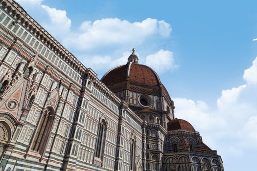Side view of famous historical Florence Duomo, Santa Maria Del Fiore, on cloudy blue sky background.