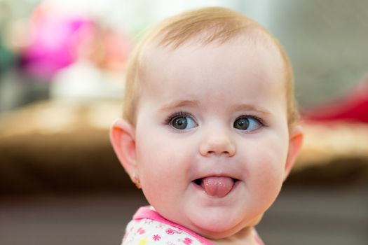 Happy cute little one year old girl indoor smiling and stick your tongue