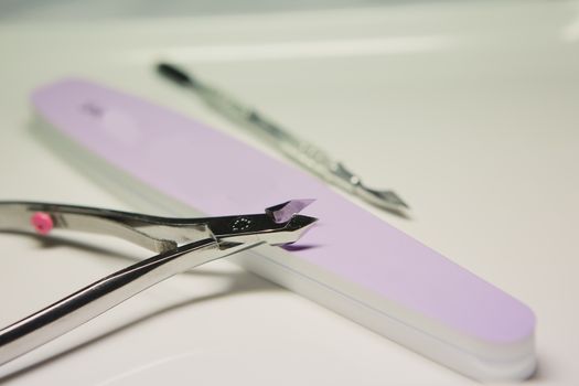 Closeup shot of a woman in a nail salon receiving a manicure by a beautician with nail file. Woman getting nail manicure. Beautician file nails to a customer.