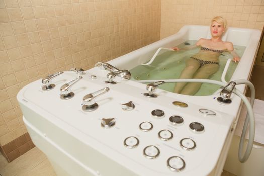 A woman and a hydro massage. She receives medical treatments for relaxation.