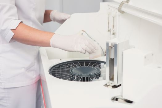 Lab tech loading samples into a chemistry analyzer in clinic