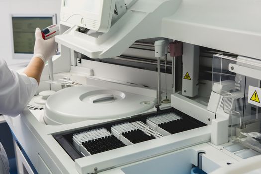 Lab tech loading samples into a chemistry analyzer in clinic