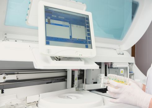 Lab tech loading samples into a chemistry analyzer in clinic