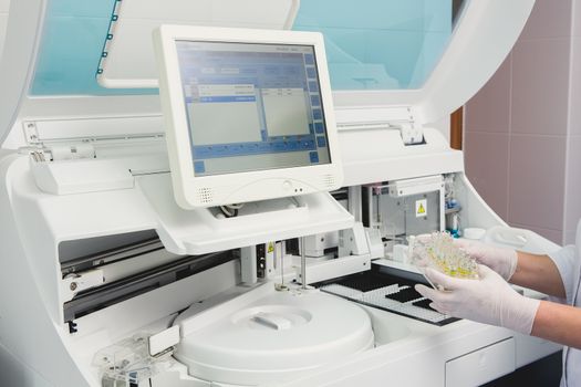 Lab tech loading samples into a chemistry analyzer in clinic