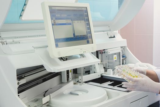 Lab tech loading samples into a chemistry analyzer in clinic