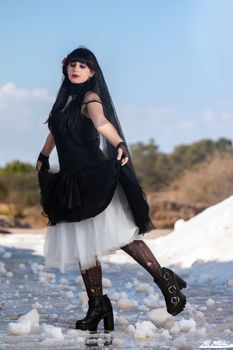 View of a beautiful young girl in gothic clothing on a salt evaporation pond.