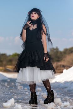 View of a beautiful young girl in gothic clothing on a salt evaporation pond.