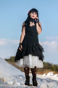 View of a beautiful young girl in gothic clothing on a salt evaporation pond.