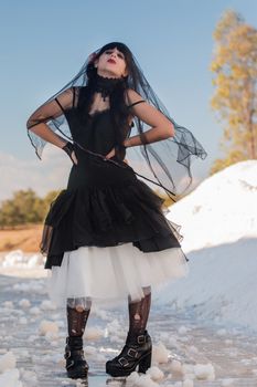 View of a beautiful young girl in gothic clothing on a salt evaporation pond.