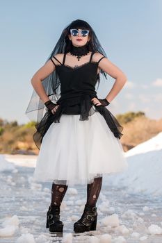 View of a beautiful young girl in gothic clothing on a salt evaporation pond.