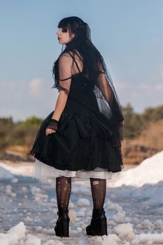 View of a beautiful young girl in gothic clothing on a salt evaporation pond.