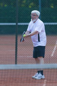 Senior man playing tennis on a gravel court