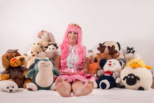 young girl in a bedroom in a pink cute dress and many toys.