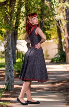 View of a young woman with a simple spring dress posing on the park.