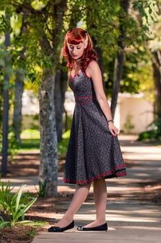 View of a young woman with a simple spring dress posing on the park.